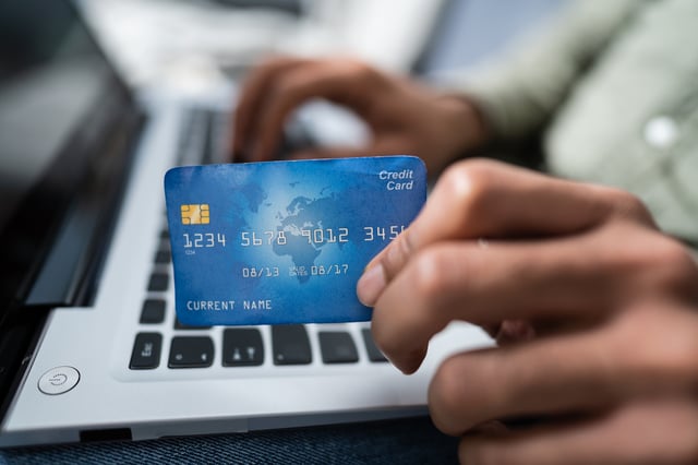 A Person Hand Using Debit Card While Shopping Online