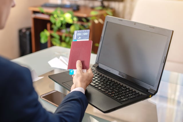 Businessman Holding Airline Ticket And Passport Buying On The Internet