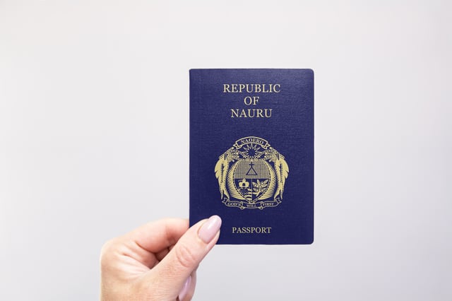 Close Up Of A Nauru Passport Held In Hand Against A Plain White Background
