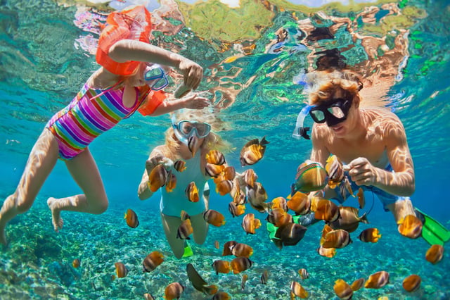 Family snorkeling with fish underwater