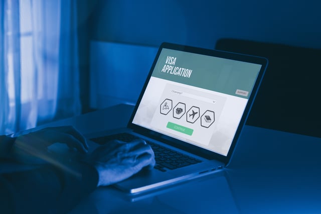 Hands Filling Visa Application Form On Laptop