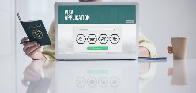 Man Holding Passport Filling Visa Application Form On Laptop