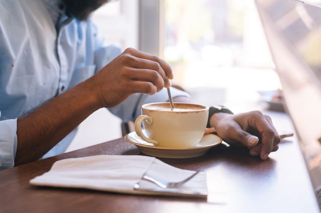 Man stirring a cup of coffee on a bar table