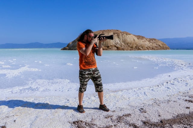 Man Tourist With Camera On The Salty Surface Of The Lake Assal