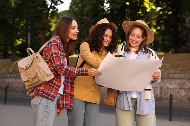 Three tourists looking at map outdoors